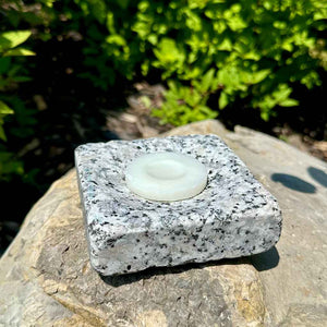Upcycled granite soap dish on rock holding small circular soap.