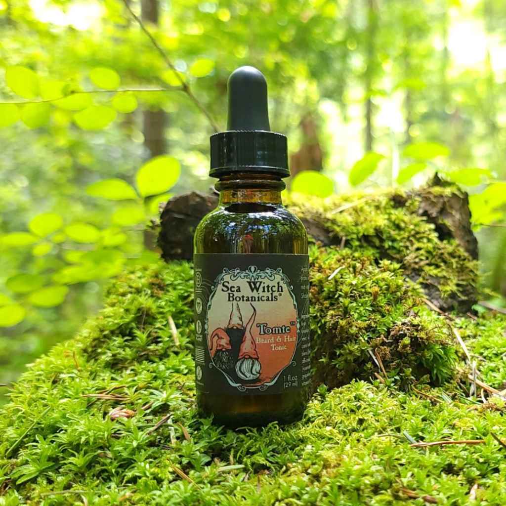 Tomte™ Beard &amp; Hair Tonic in a small amber glass dropper bottle, pictured on a mossy area in a forest