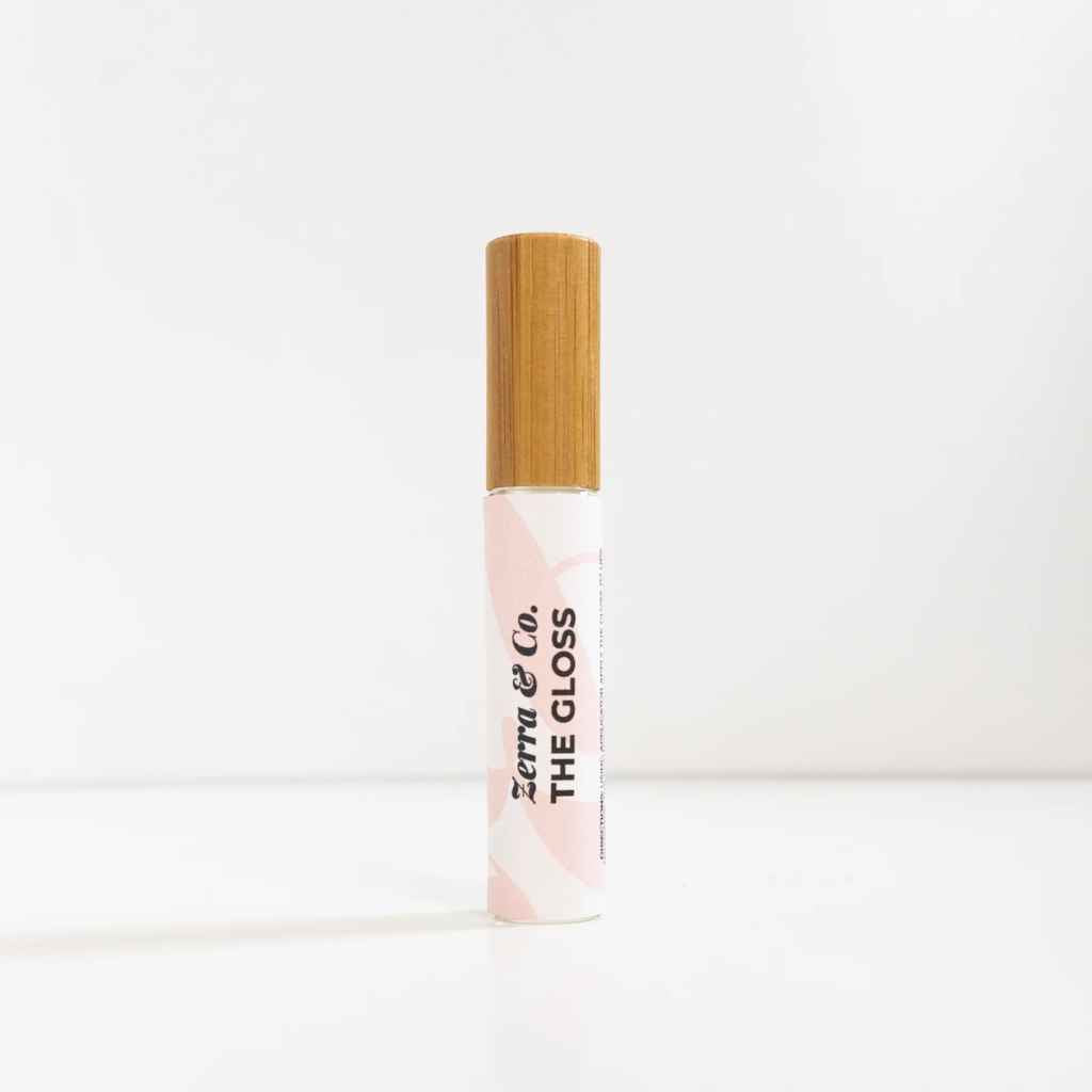 A glass tube of lip gloss with a bamboo top made by Zerra & Co.