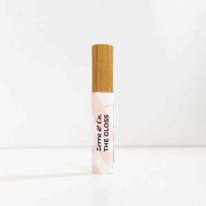 A glass tube of lip gloss with a bamboo top made by Zerra @ Co.