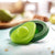 two avocado huggers displayed next to wooden cutting board