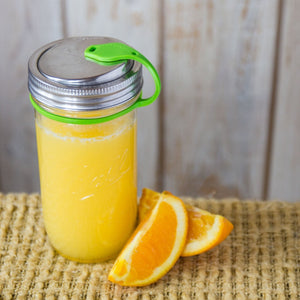 orange juice in mason jar with eco jarz lid and green pop top, orange slices and eco jarz packaging