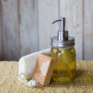 mason jar with yellow soap and stainless steel dispenser top, next to natural soaps