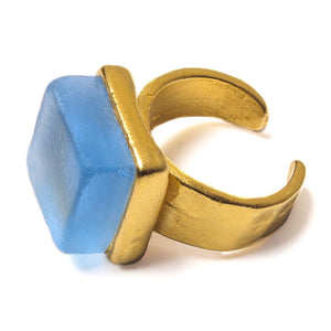 Close up of a blue recycled glass cocktail ring with a gold band and a square stone