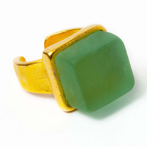 Close up of a green recycled glass cocktail ring with a gold band and a square stone