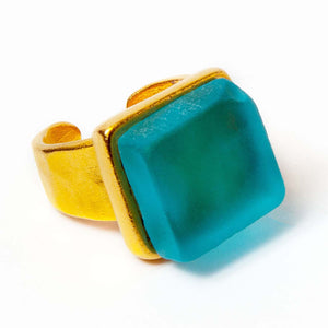 Close up of a light blue recycled glass cocktail ring with a gold band and a square stone