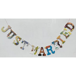 multicolored collage style "Just married" garland, hanging on white wall