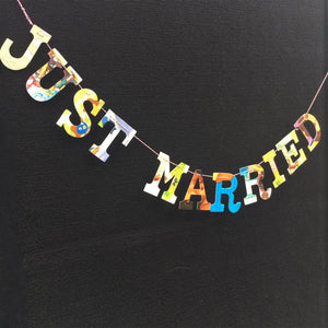 multicolored collage style "Just married" garland, hanging on black canvas