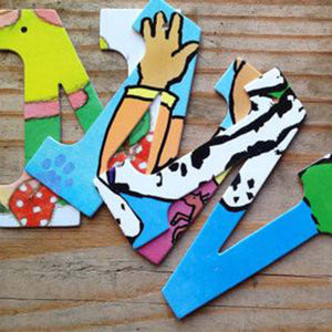 Three different designs of the letter "N" placed on unfinished wood. Designs feature pages of children's picture books