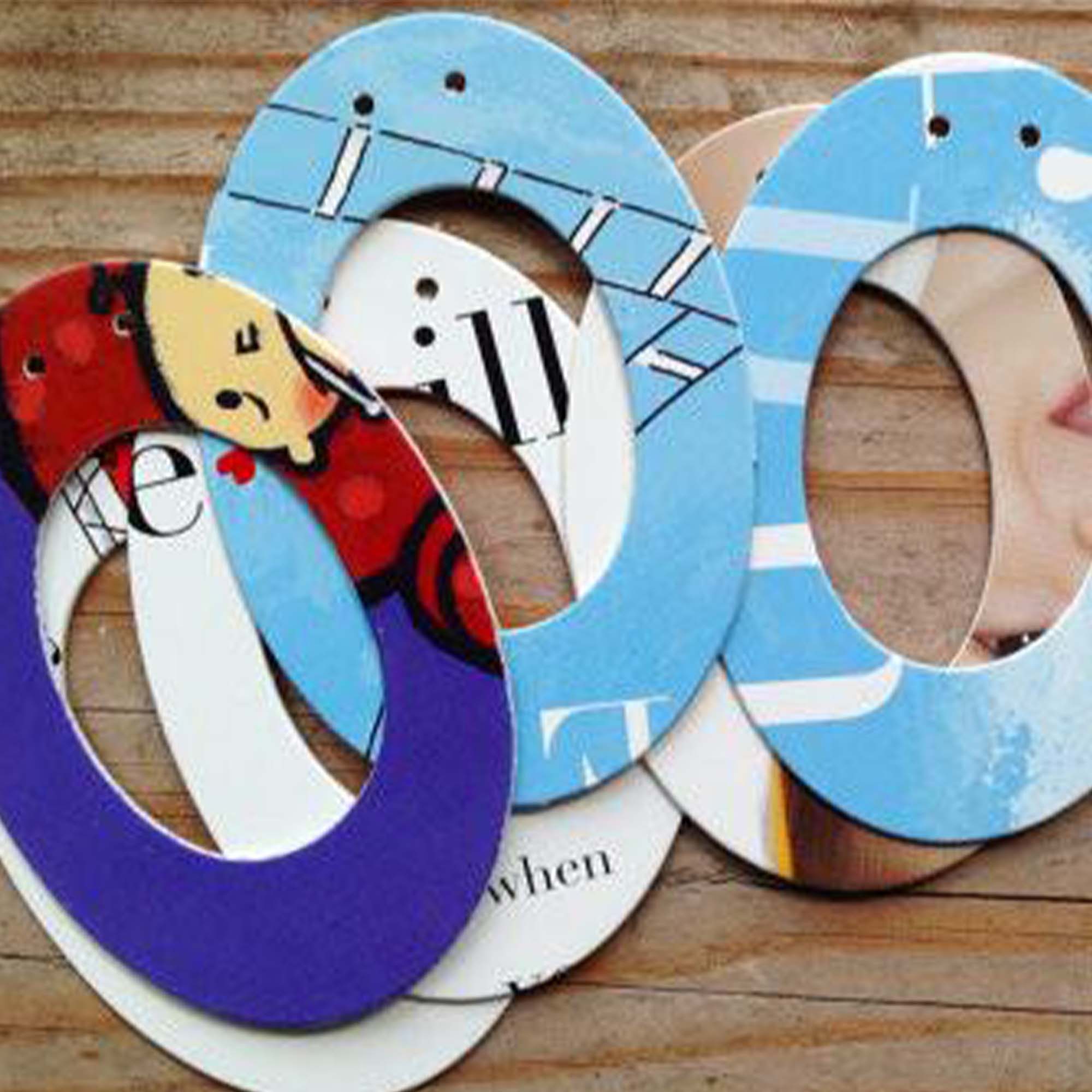 six designs of the letter "O", placed on exposed wood. Each design uses pages from children's picture books