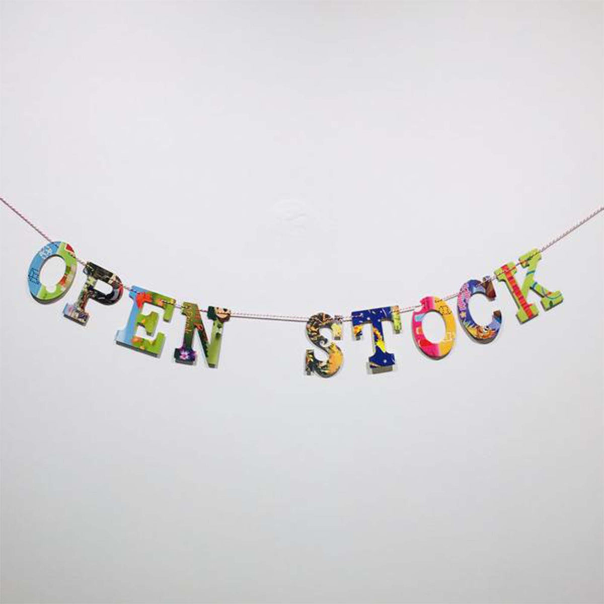 multi-colored, collage style &quot;open stock&quot; garland displayed  hanging on white wall