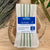 4 pack of creme and green striped cotton tea towels, displayed with calming herbs and exposed wood