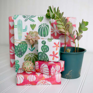 various sized gifts wrapped with wrappily paper. green and red succulent designs. reversible.