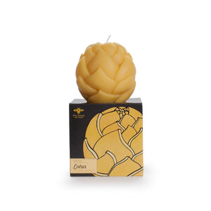 sculpted Lotus sphere candle, natural colored, sitting on top of black cardboard packaging, with golden lotus design on front