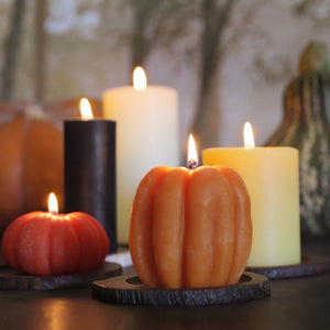 five candles for fall in various orange, glowing yellow, and dark hues