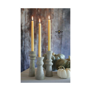 three natural colored 100% Pure Beeswax tapers in rustic stone holders, with autumn backdrop featuring green and white pumpkins