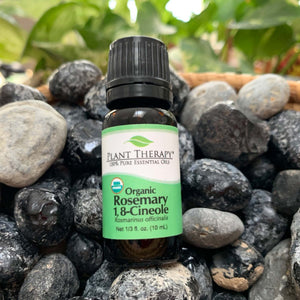 10 ml black bottle with green label. (organic rosemary 1, 8-cineole) essential oil blend displayed on assorted rocks