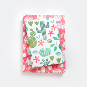 two gifts, stacked. wrappily paper with red and green succulent design, reversible