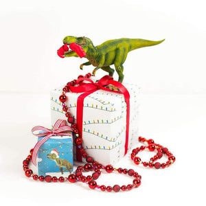 two packages wrapped in TRex and string light paper, with a toy dinosaur on top