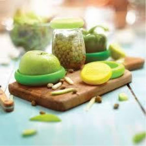 various green fruits and vegetables cut on wooden cutting board, featuring food savers attached to sliced produce.