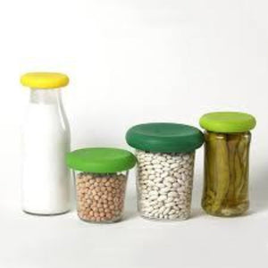 bottle of milk, glass of chic peas, glass of white beans, glass of pickled peppers all with food saver lids attached
