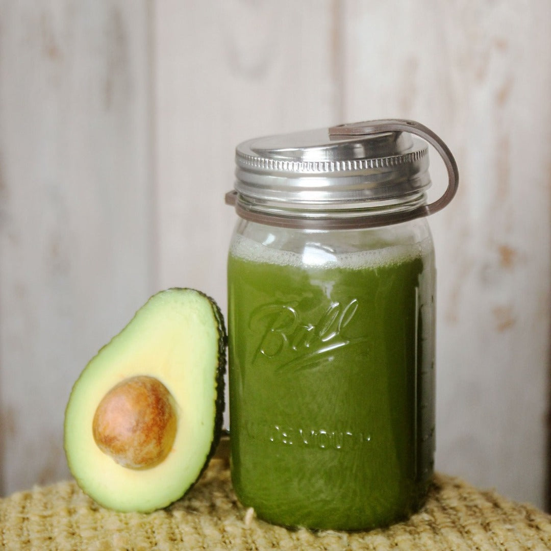 avacado slice resting on mason jar filled with green juice, includes eco jars lid and brown pop top