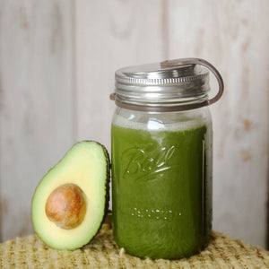 avacado slice resting on mason jar filled with green juice, includes eco jars lid and brown pop top