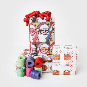 two packages wrapped in Warhol paper next to spools of ribbons.